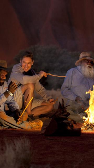Sitting around a campfire at night | Voyages Indigenous Tourism
